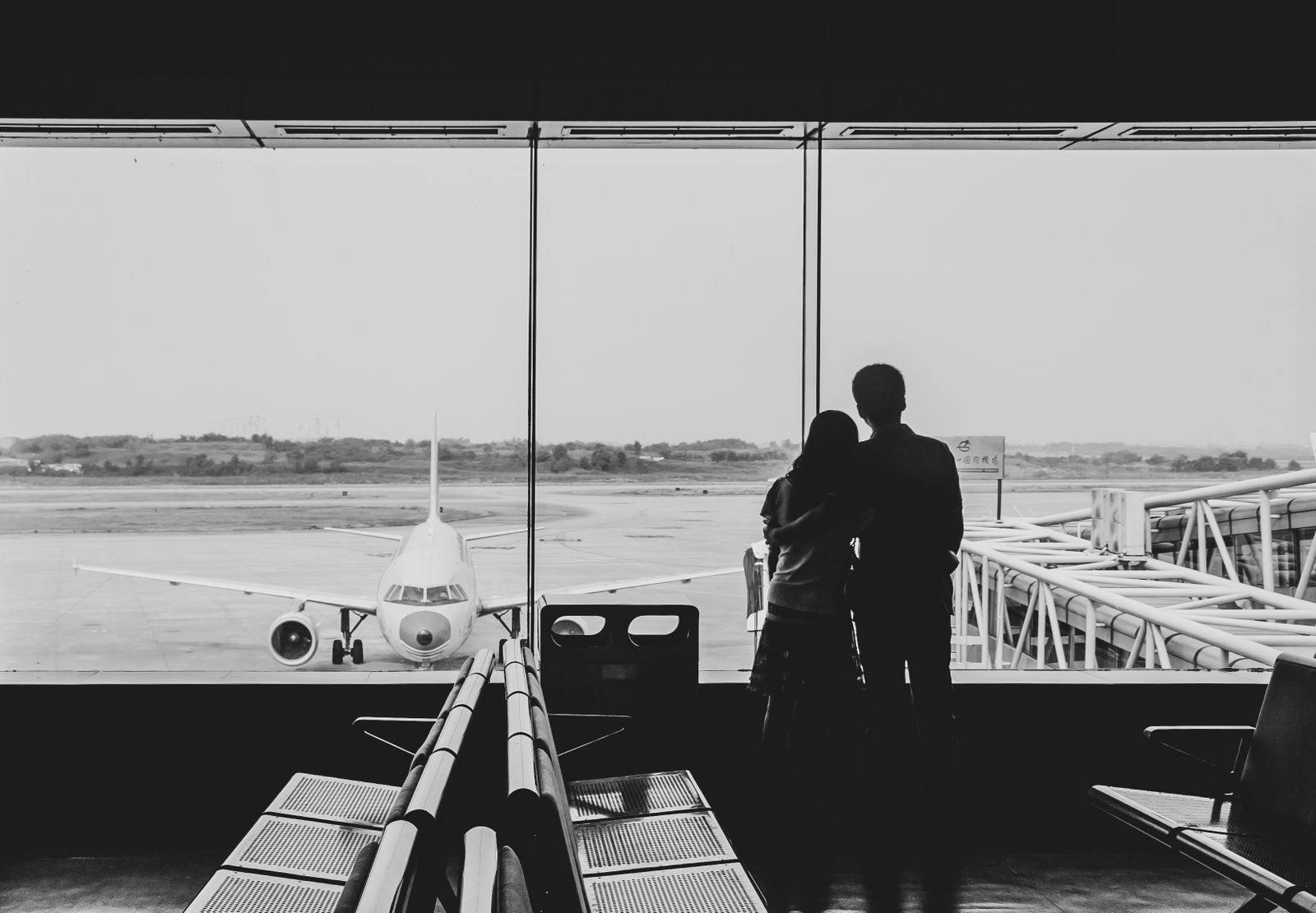 Casal observando avião pela janela do terminal